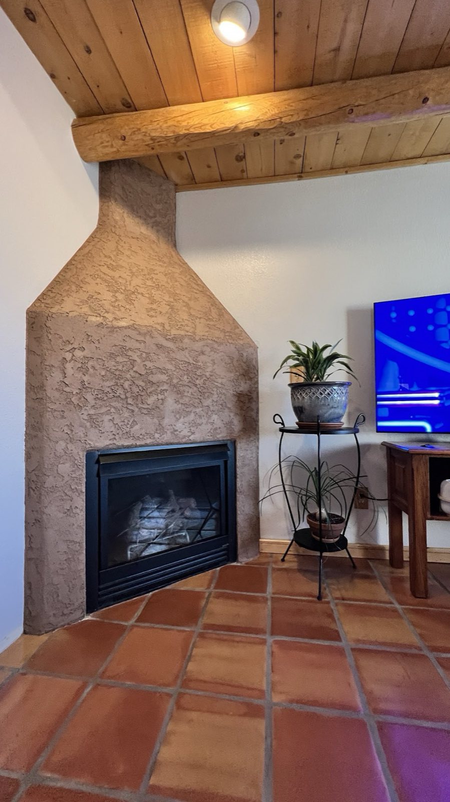 The same Kiva fireplace afterwards — tiles gone, a new texture and color worked over the whole face, terracotta floor and timber ceiling either side.